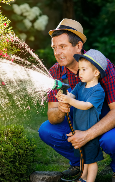 homme et son fils utilisant l'eau de pluie pour arroser le jardin